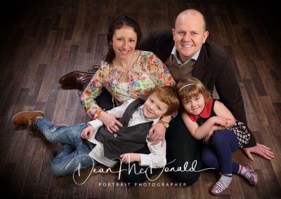 Family sitting together on floor. multi coloured attire.