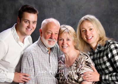 Traditional family portrait on gry backdrop.