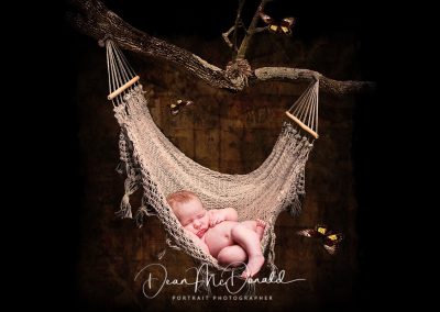 A baby asleep in a string hammock. with butterflies