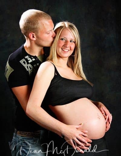 Pregnant couple embracing in studio.