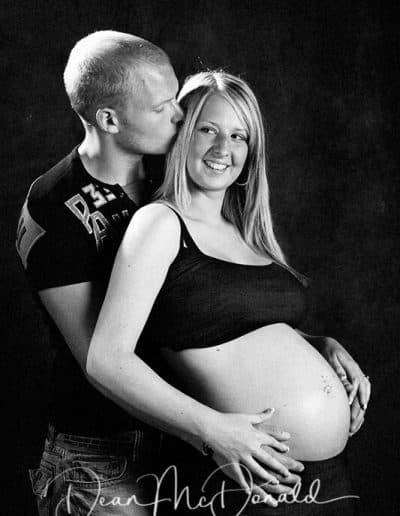 Pregnant couple embracing in studio.