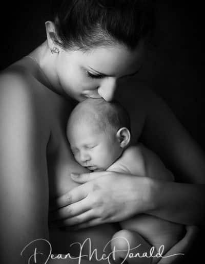 Intimate portrait of a mother kissing her newborn.