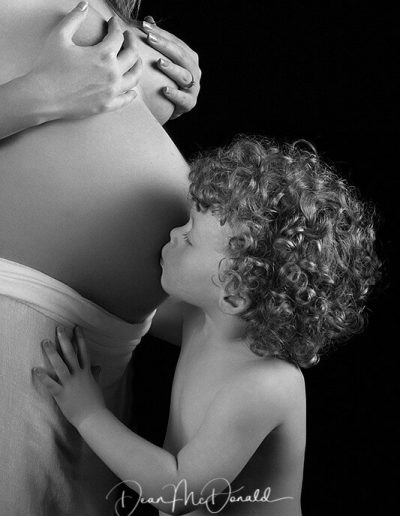 Proud mum to be with child kissing baby bump - Low-Key background.