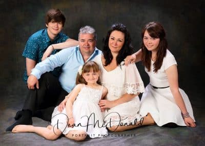 Family portrait sitting on the floor with matching colour tones.