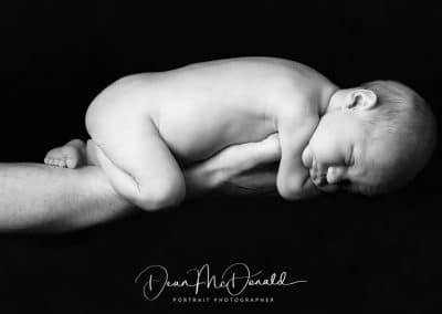 Newborn on his fathers arm.