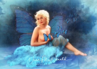 Studio montage of a teenager with butterfly wings in a fluffy dress with clouds smoke and more butterflies.