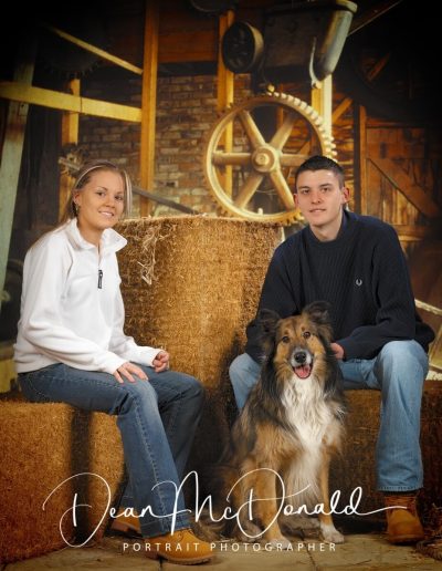 Two teenagers with a collie dog in a barn