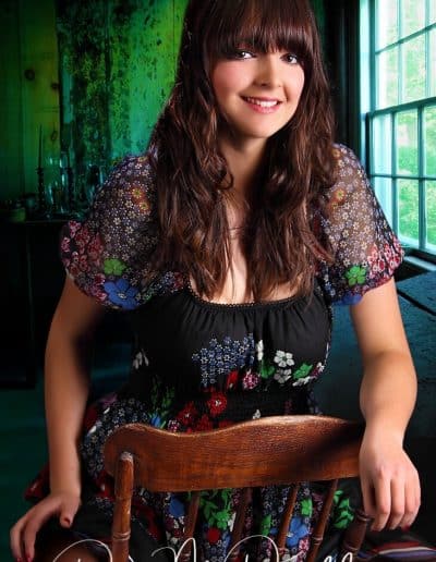 Woman in floral dress, seated indoors.