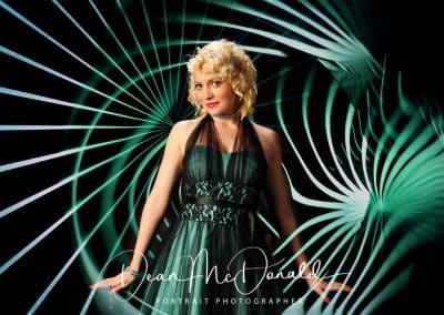 Elegant young woman in a striking green dress and matching creative background.