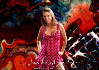 A teenage woman in a red and black polka dot dress against a vibrant multicolor backdrop..