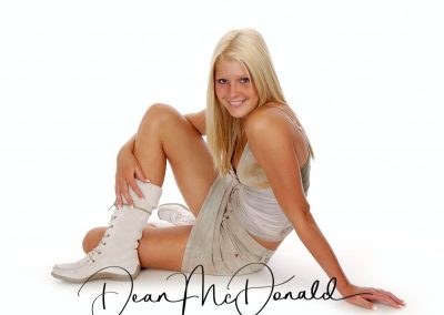 A teenager sitting on floor in boots and khaki outfit.