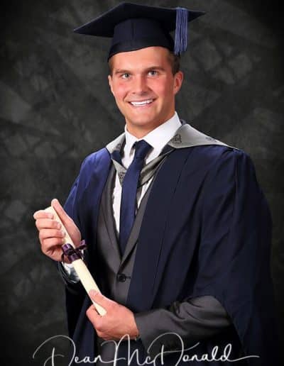 Graduate holding diploma in cap and gown.
