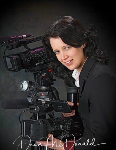 Person posing with professional video cameras.