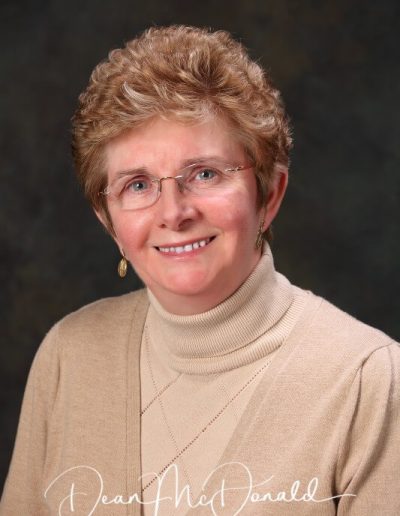 Woman in light sweater, neutral background.