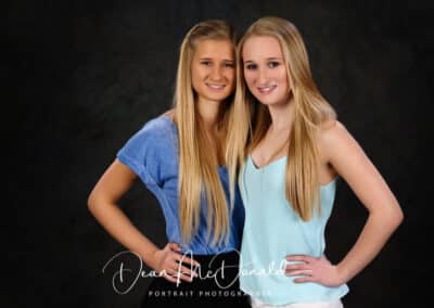 Two girls posing together, smilingin blue tops.